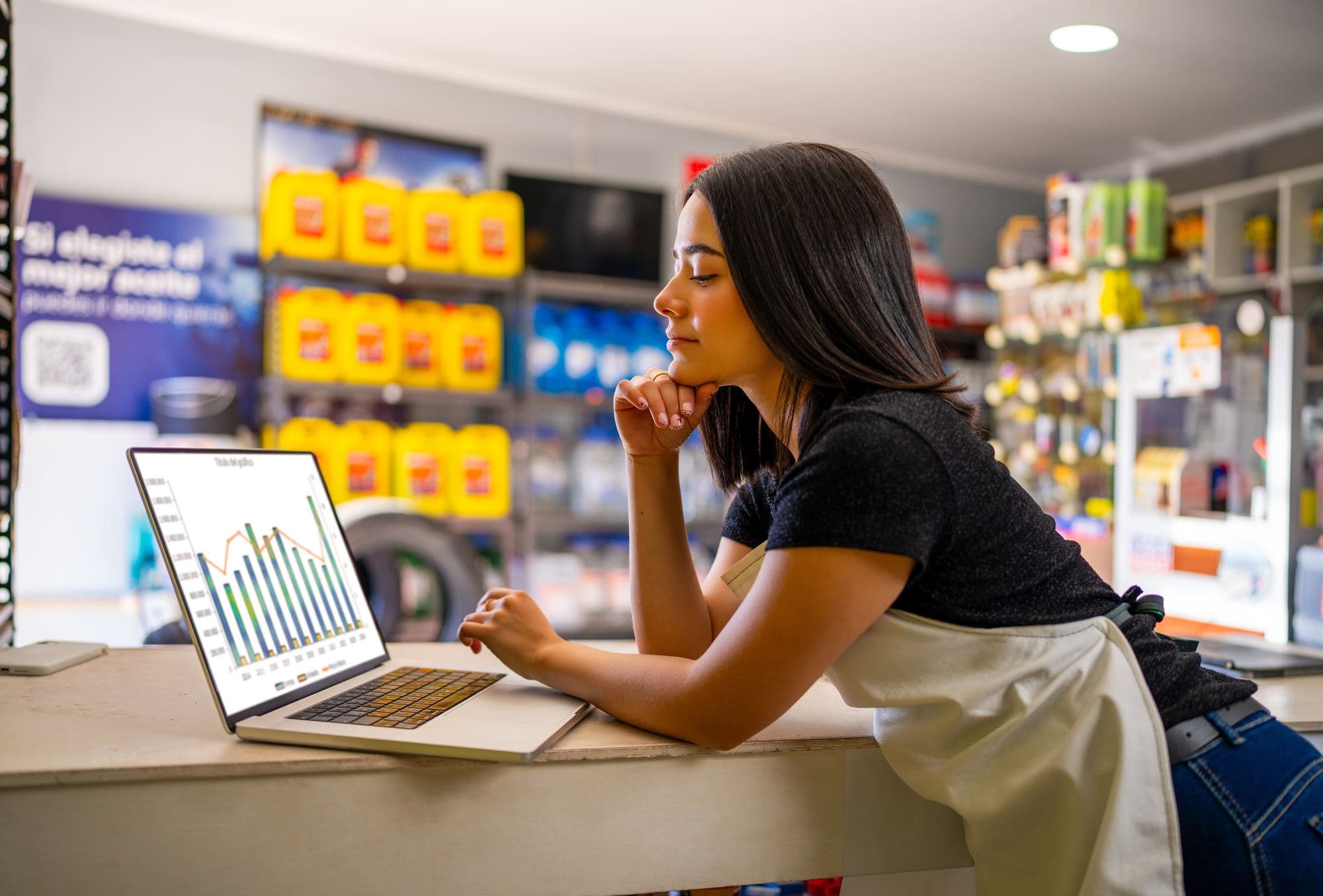 A shop owner reviewing sales figures on a laptop