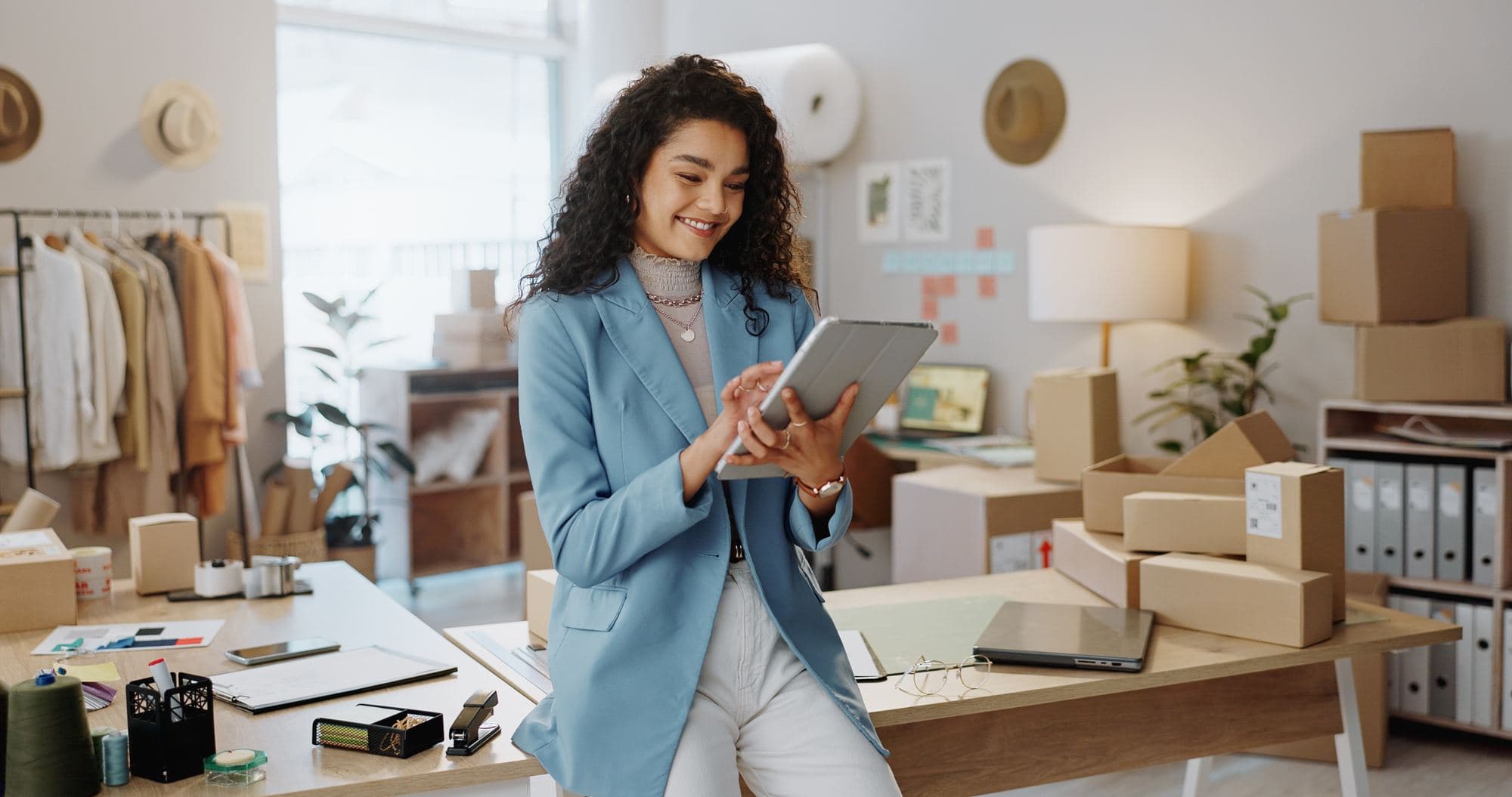 A self-employed owner packing orders and working from a tablet